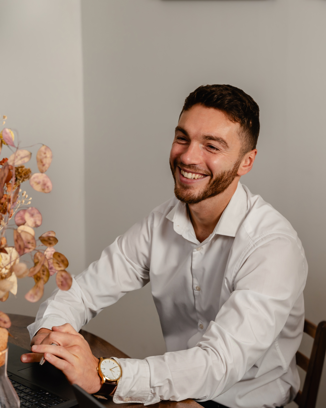 Blaine Rowan smiling at a table in a smart white shirt.