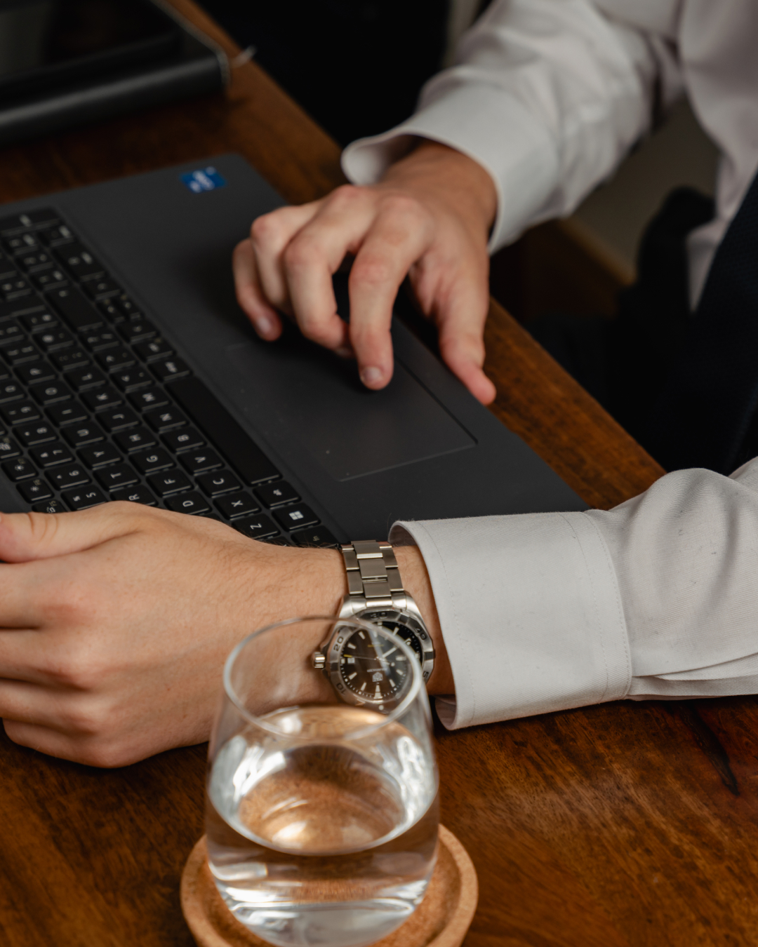 Hands using a laptop wearing a sliver watch.