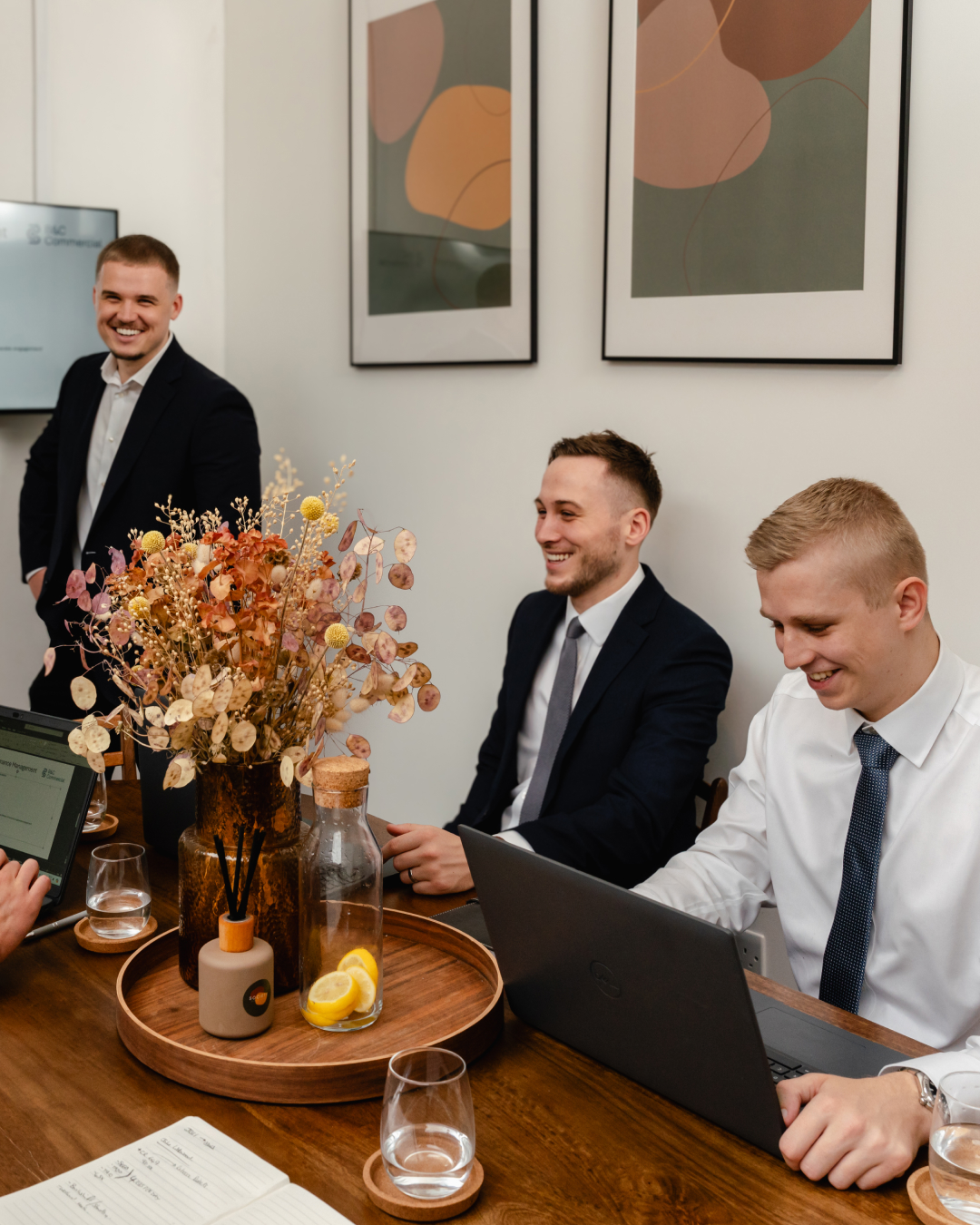 Jamie, Ben and Sam sharing a smile in the office. There are dried flower on the table.